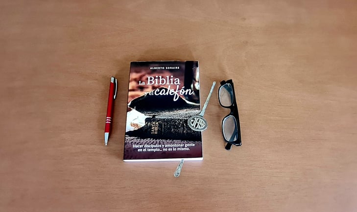 a book with a pen and glasses on a table