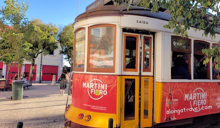 Yellow & red tram is doing its regular route on a street of Lisbon, Portugal