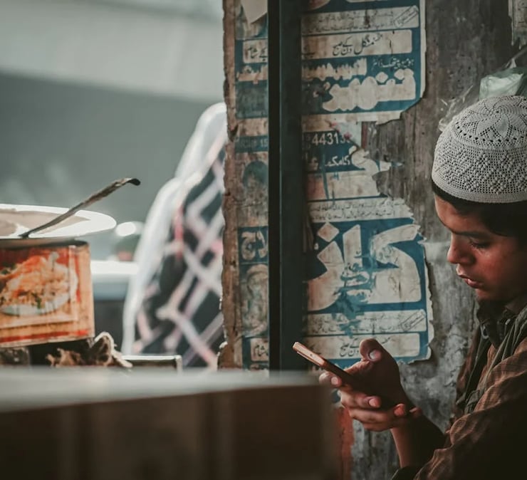 a young boy is looking at his cell phone