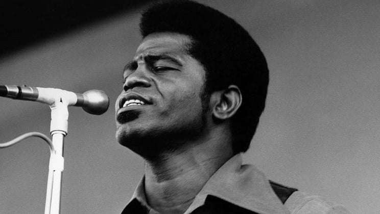 Black and White Portrait of James Brown on Stage singing into a microphone