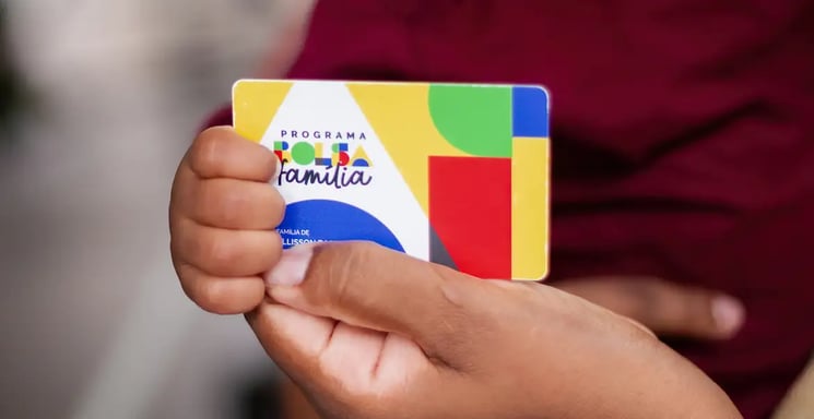 Uma criança segurando o cartão do bolsa família.