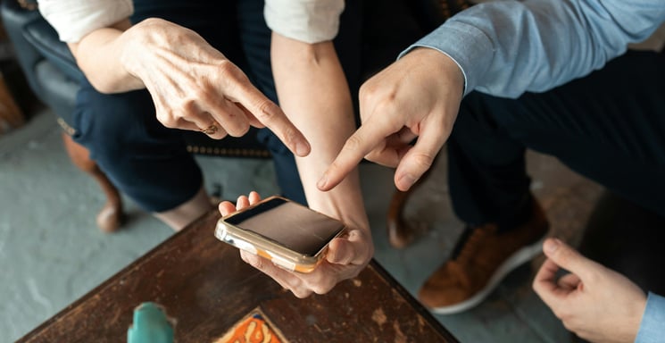 pessoas segurando um celular e apontando o aplicativo do serasa.