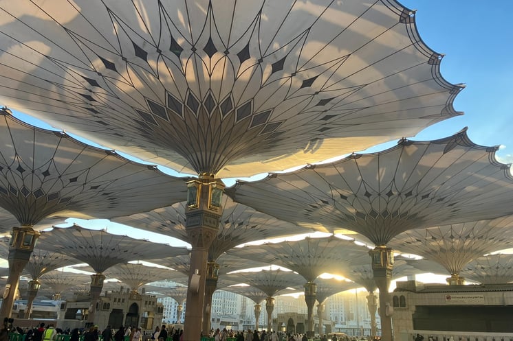 a group of people standing around a large umbrella of Medina, Saudi Arabia