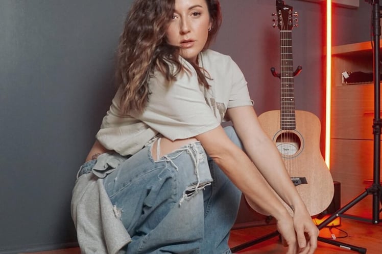 a woman sitting on a wooden floor next to a guitar