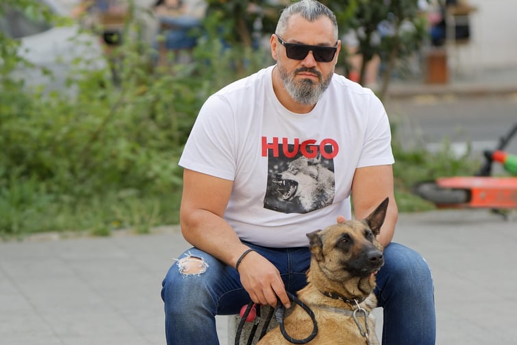 Business owner sitting with his dog Hugo who is also wearing a hugo the dog shirt