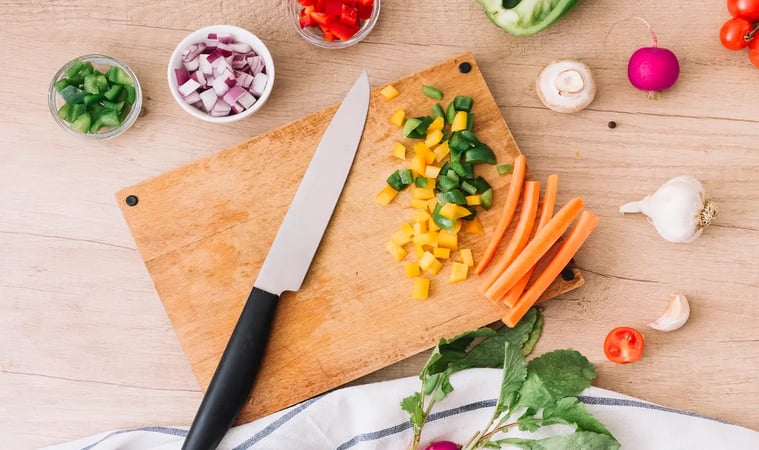 Chopped vegetables on a cutting board with a knife.