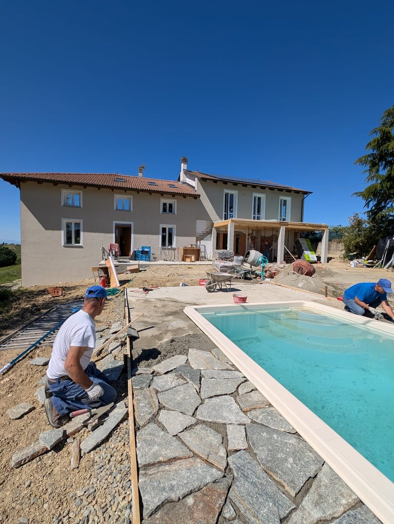 Professional contractors installing a stone pool deck patio to a swimming pool by Monferrato Homes
