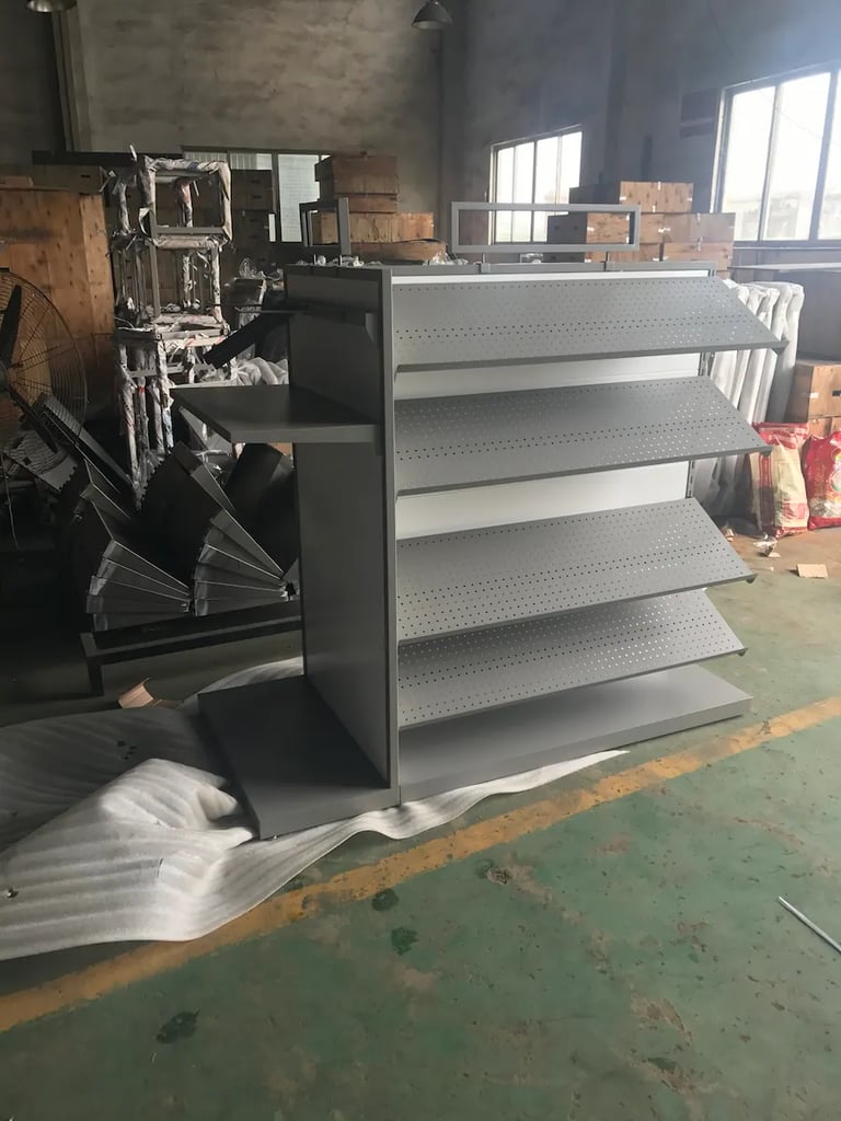 Double-sided metal gondola shelving unit with grey perforated pegboard panels in a warehouse.