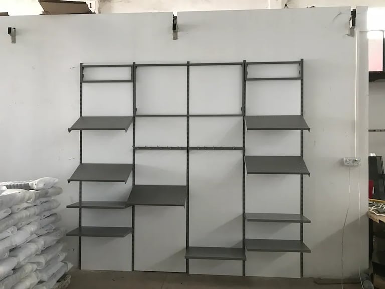 Industrial gray metal wall shelving unit with adjustable storage racks and display shelves.
