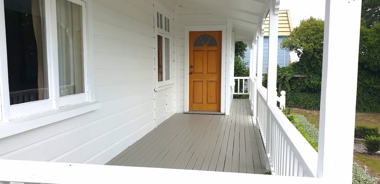 White weatherboard home with porch detailing, freshly painted by Gee Cee Painter.