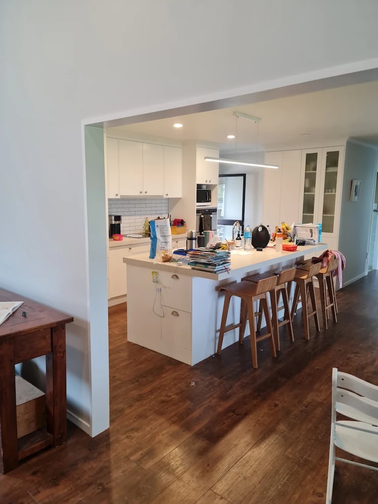 White kitchen with central island and wood floors, freshly painted by Gee Cee Painter.