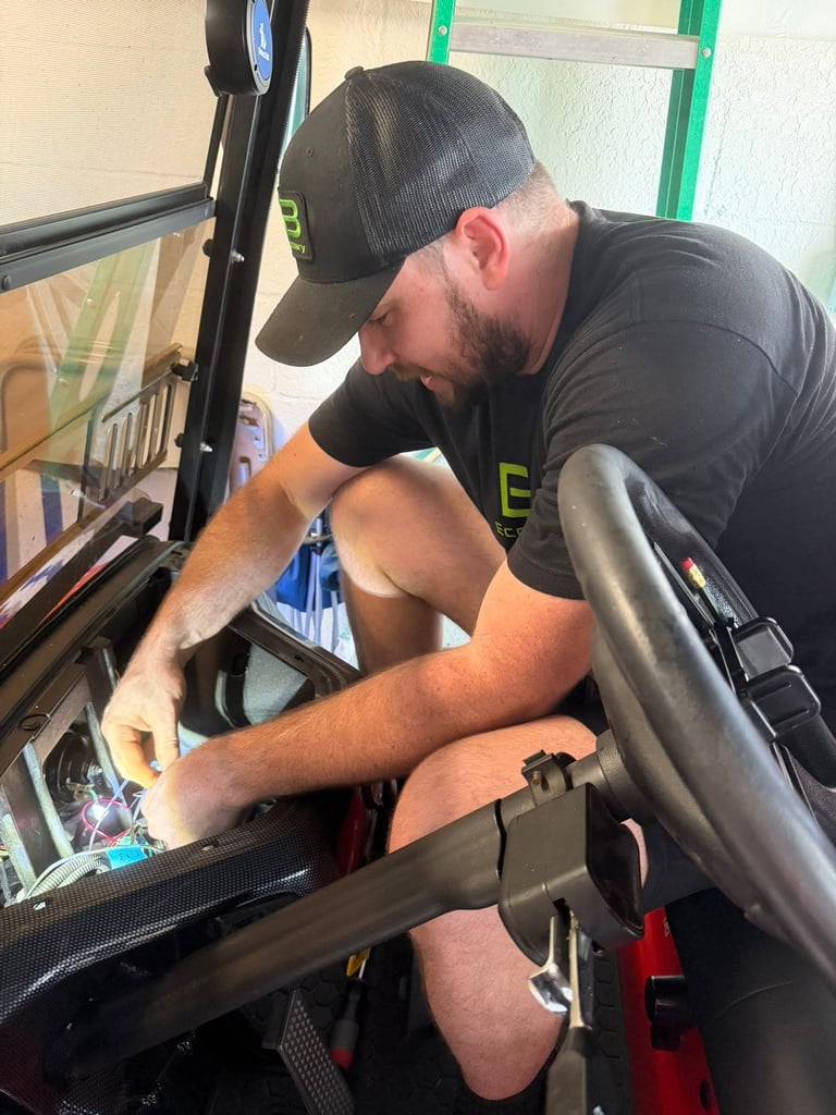 A technician performing electrical repair and battery maintenance on a custom golf cart.