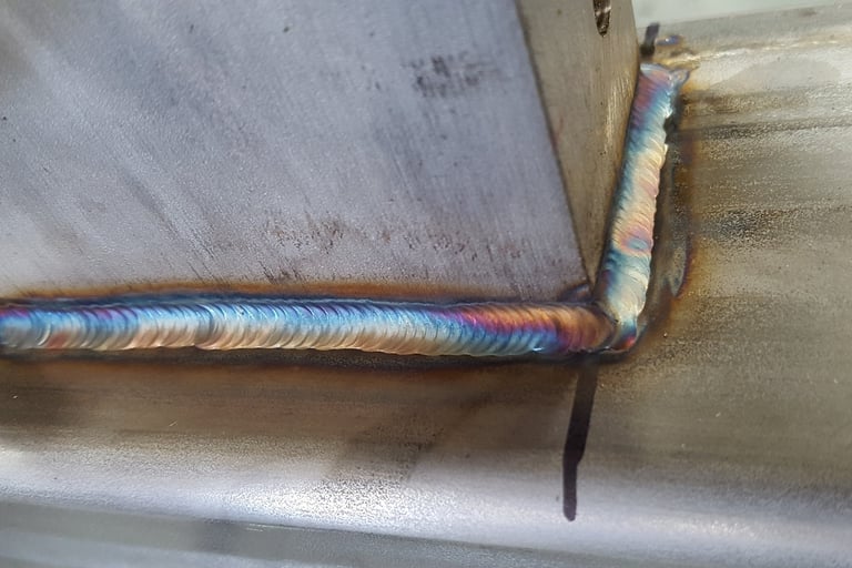 Close-up of a high-quality TIG weld on stainless steel with vibrant heat tint coloration.