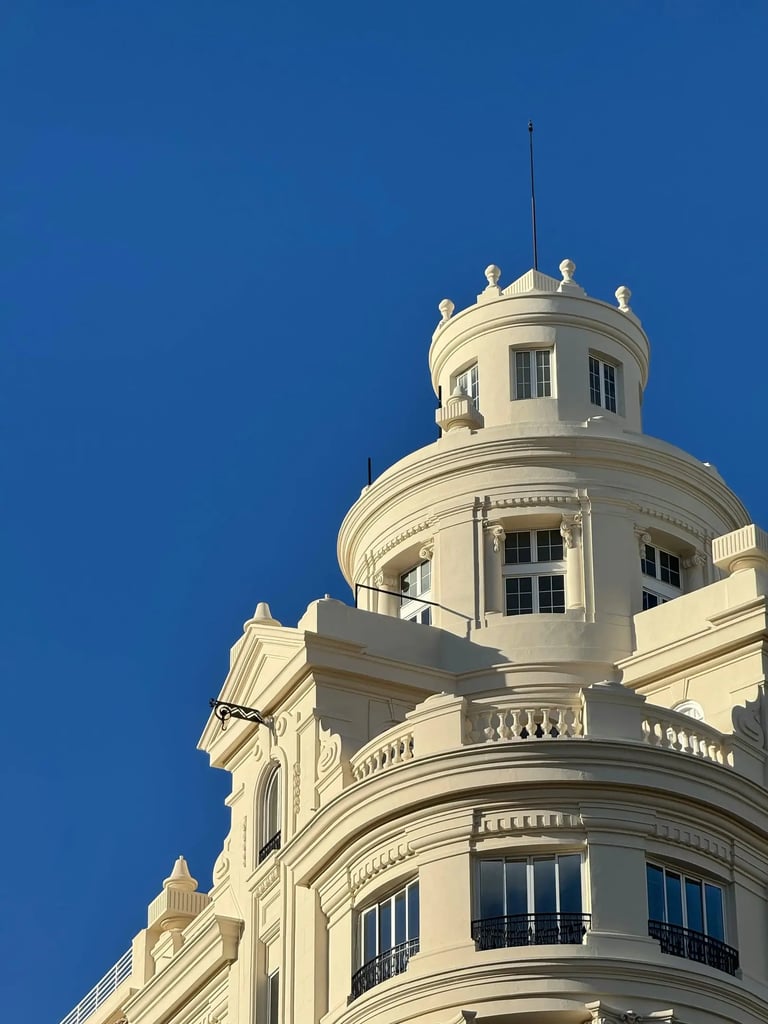 Sommet d'une tour d'architecture blanche et élégante sous un ciel bleu intense, évoquant un projet d