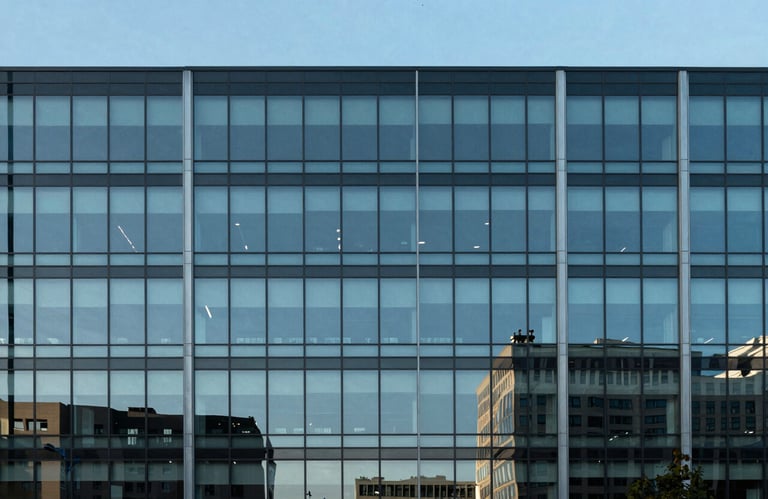 The minimalist glass facade of a modern corporate building reflecting a clear blue sky in a North American business district.