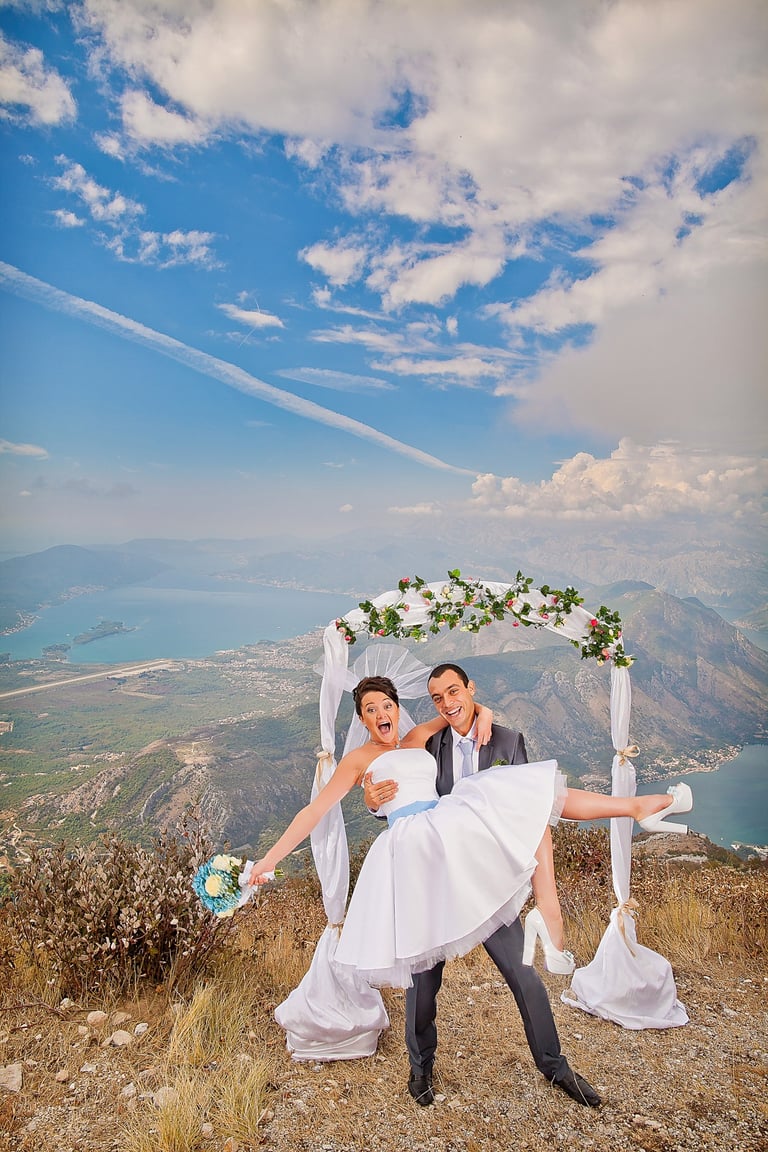 Groom lifting the bride, standing on high mountain above Tivat and Kotor