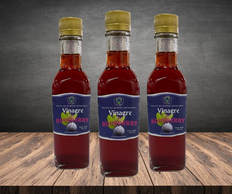 Tres botellas de vidrio de vinagre de arándanos artesanal sobre una mesa de madera rústica con fondo