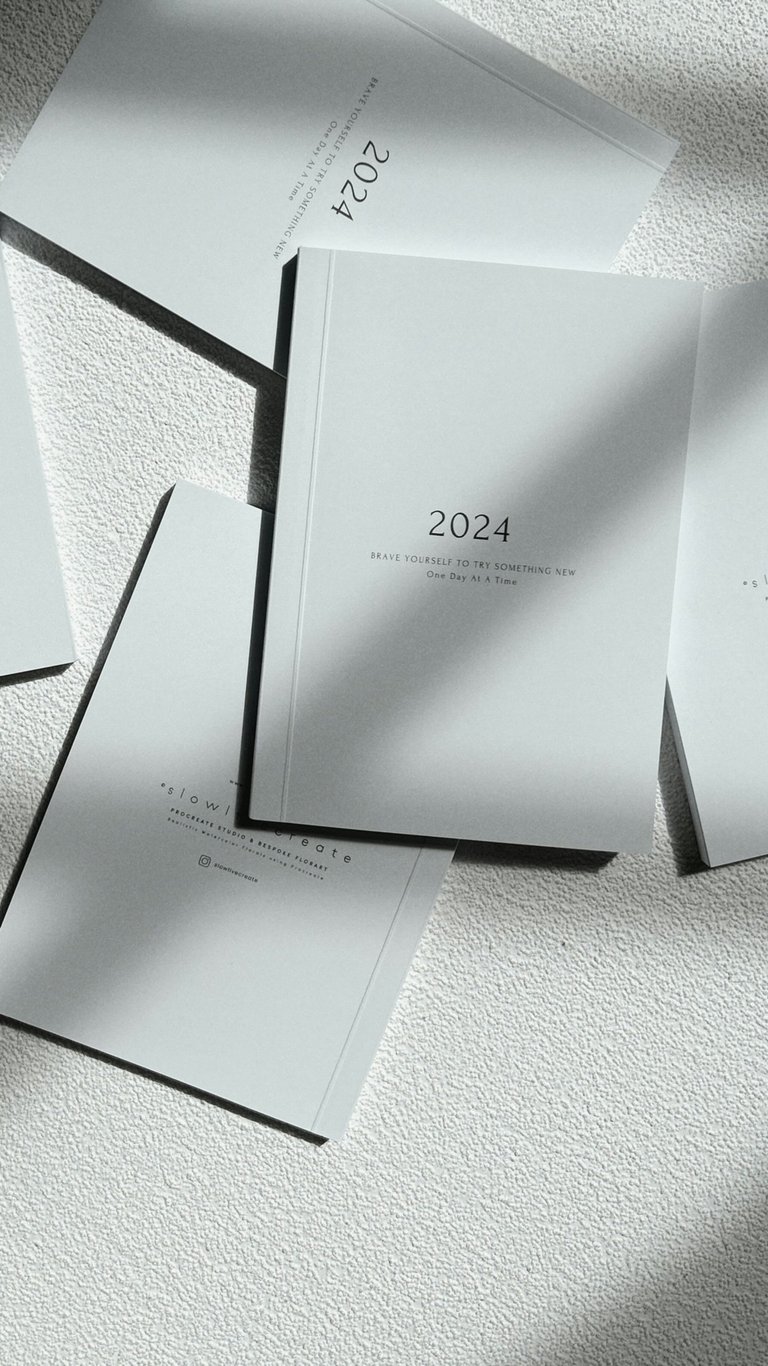 Flat lay of minimalist 2024 planners and journals with elegant typography on a textured surface.