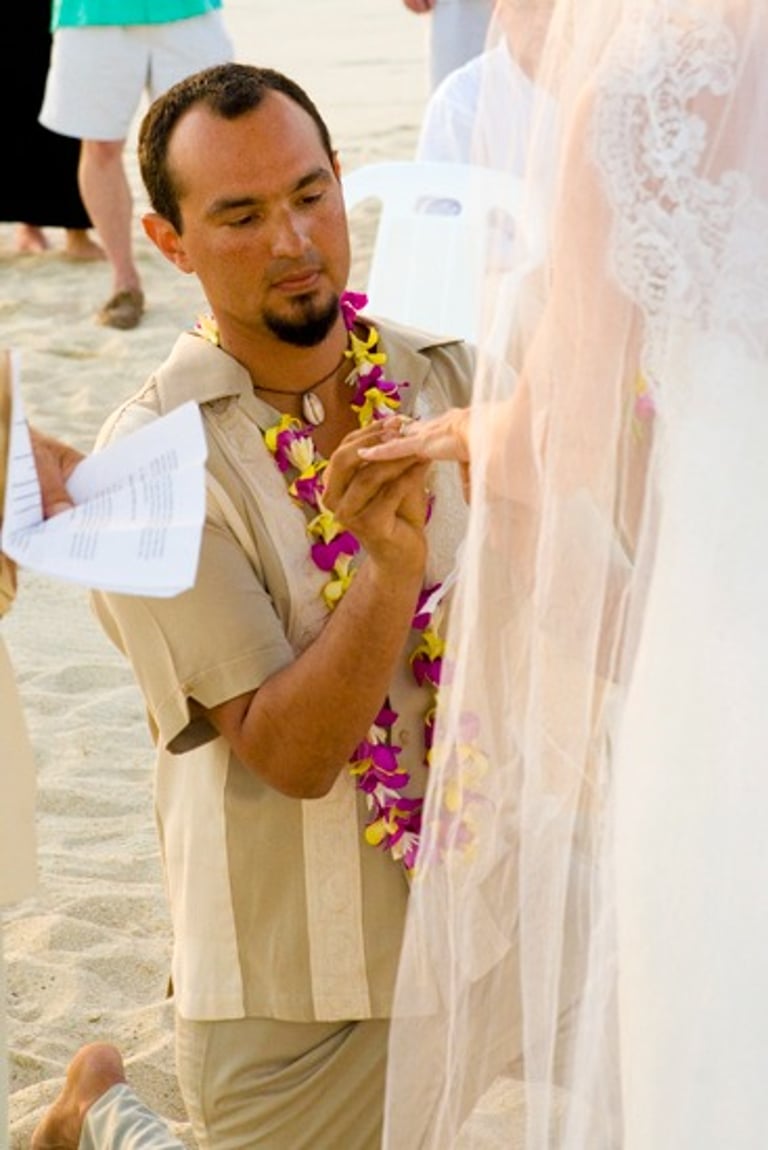 Beach Destination Wedding. Groom on his knee placing ring on Bride's finger. San Jose del Cabo, Mexico.