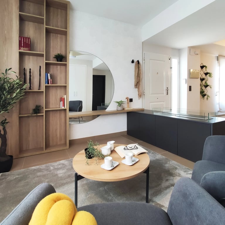 Decoración de interiores de zona relax con librería de madera, chimenea de bioetanol y butaca en San Antonio de Benaguér