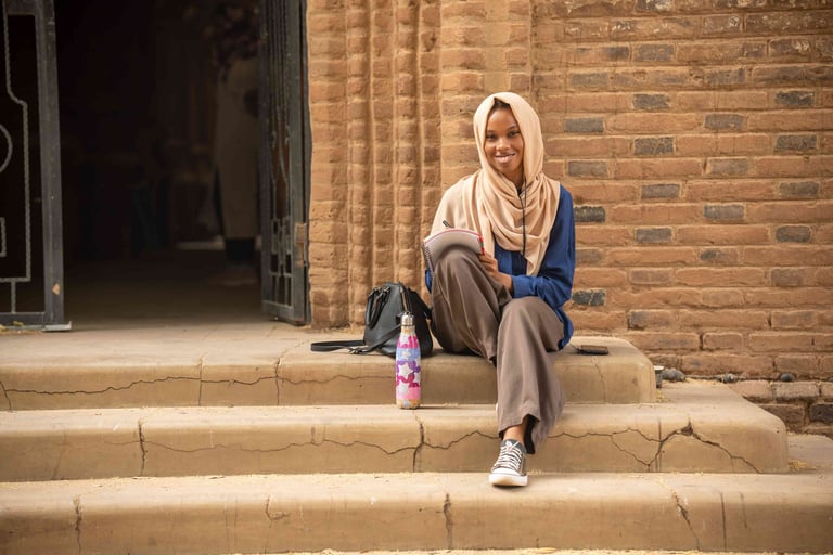 Sudanese student writing on university steps