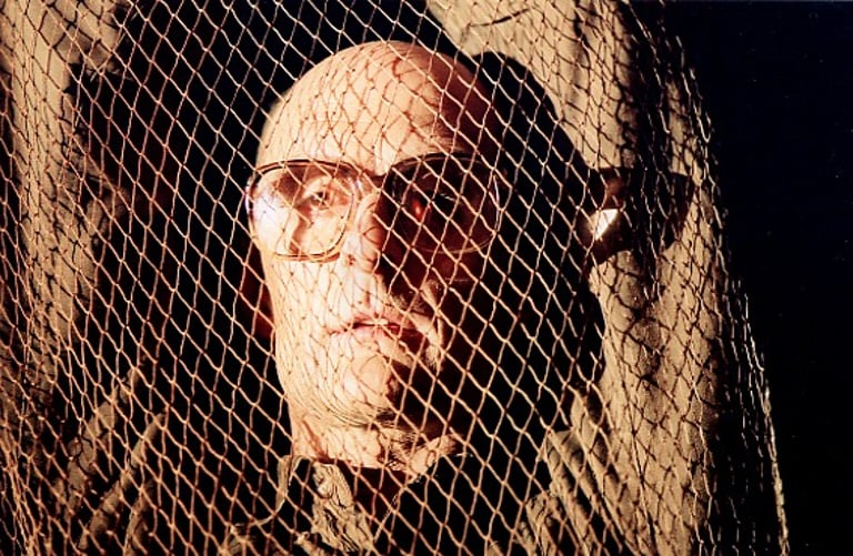 A middle-aged man with hands in the hair is trapped in a net