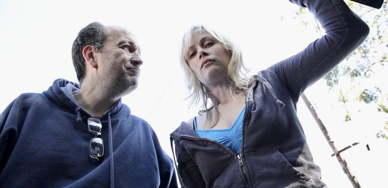 A young blonde woman and a balding middle-aged man peer down into the boot of a car