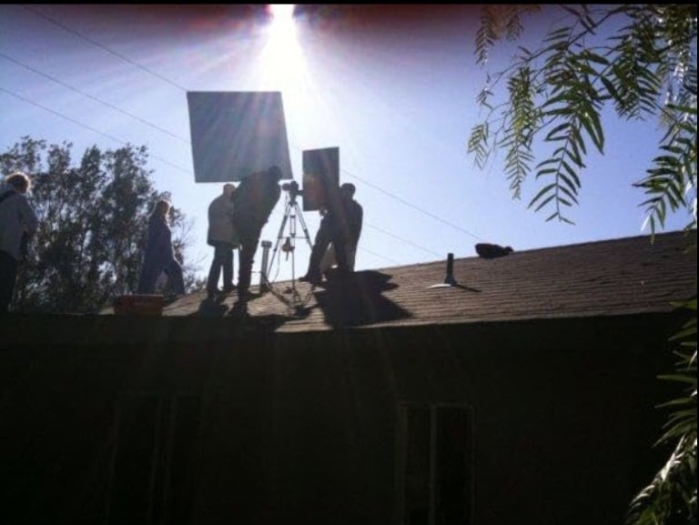 Photo of a film crew of the roof of a house taken a sunset.
