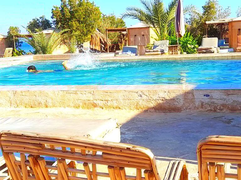 Boy swimming in the pool near the sea and bungalow at Bedouin star Egypt