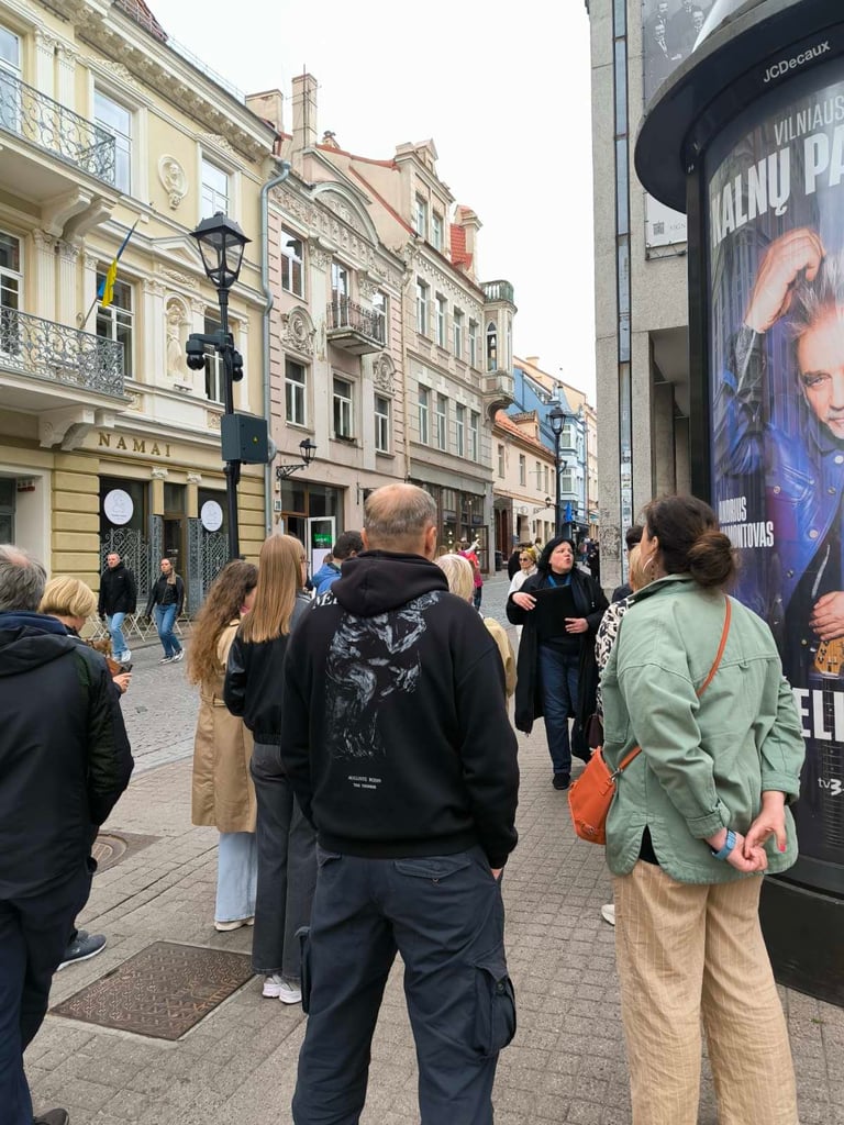 Gidė Ramutė pasakoja istorijas ekskursijos dalyvių grupei Vilniaus senamiestyje, Pilies gatvėje.