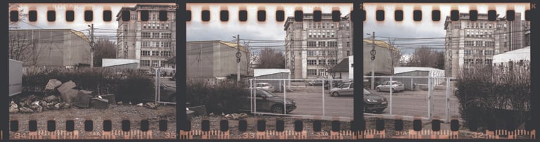 Composed photo fenced-off area with rocks and debris bare trees and buildings in the background
