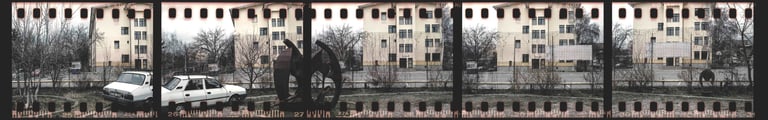 Composed photo of a city street with parked communist car and buildings, film strip