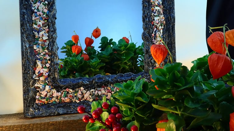 Nahaufnahme eines eleganten Spiegel-Unikats mit schwarzem Gipsrahmen und Inlay aus vielen bunten Holzstücken.