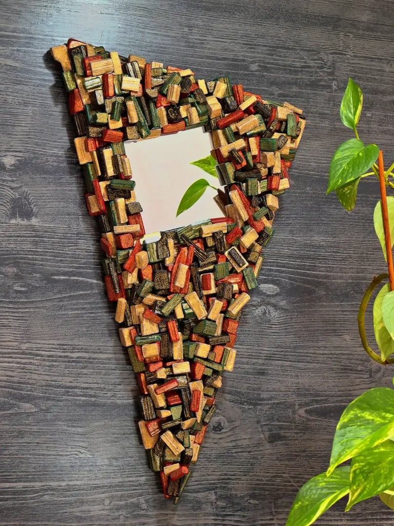 Unikaler Spiegel mit kunstvollem, dreieckigen Rahmen aus schwarz, rot, grün und gold bemalten Holzscheiten