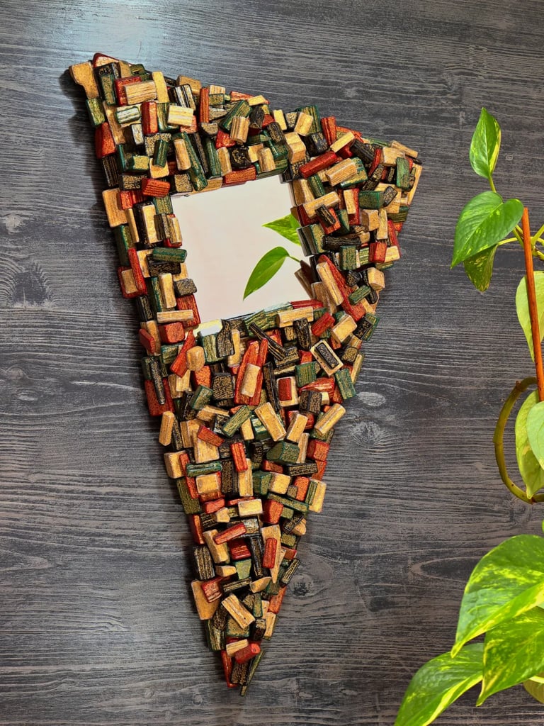 Unikaler Spiegel mit kunstvollem, dreieckigen Rahmen aus schwarz, rot, grün und gold bemalten Holzscheiten