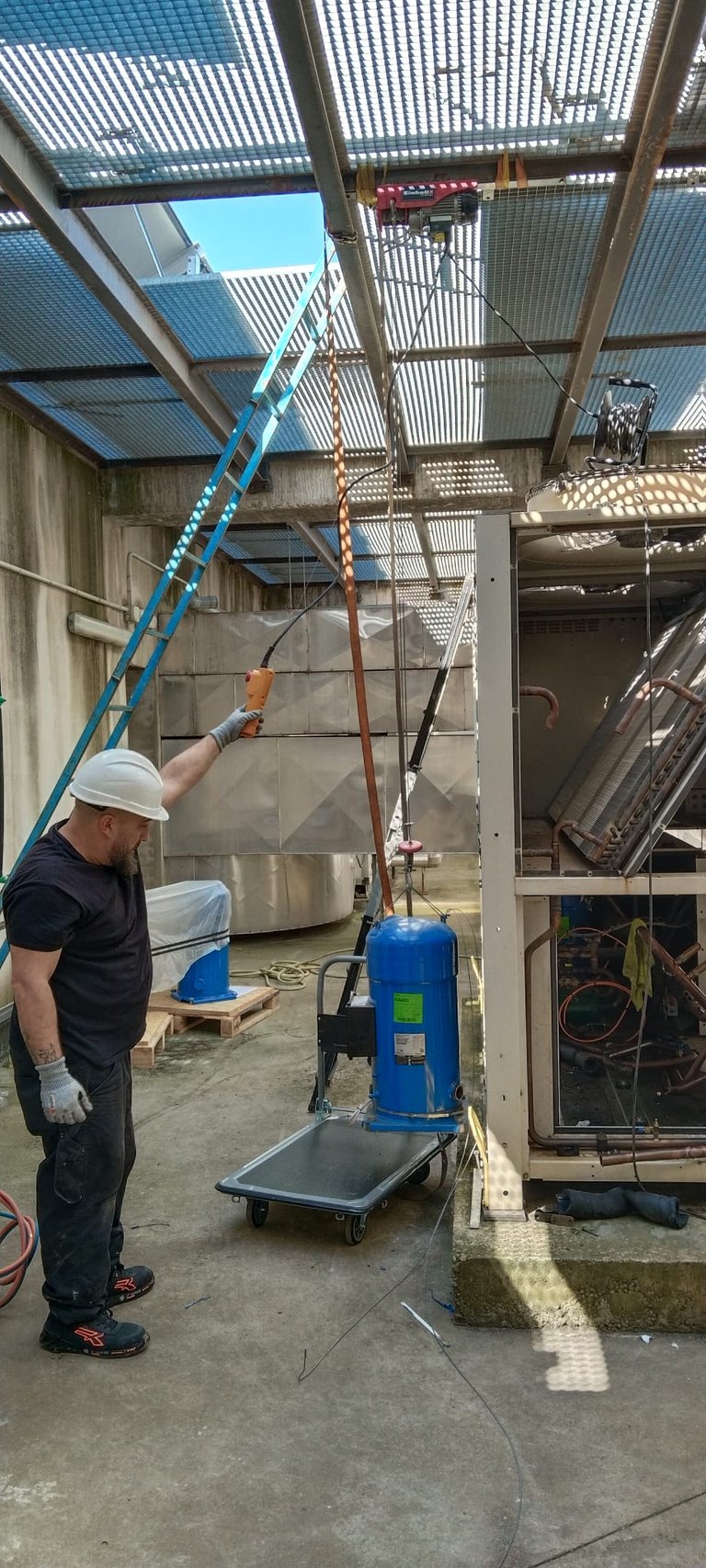 Técnico elevando un compresor con grúa, para ubicarlo en central de compresores de Refrigeración