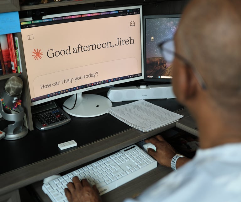 A person uses an AI chatbot interface on a desktop monitor in a home office setup with a white keyboard.