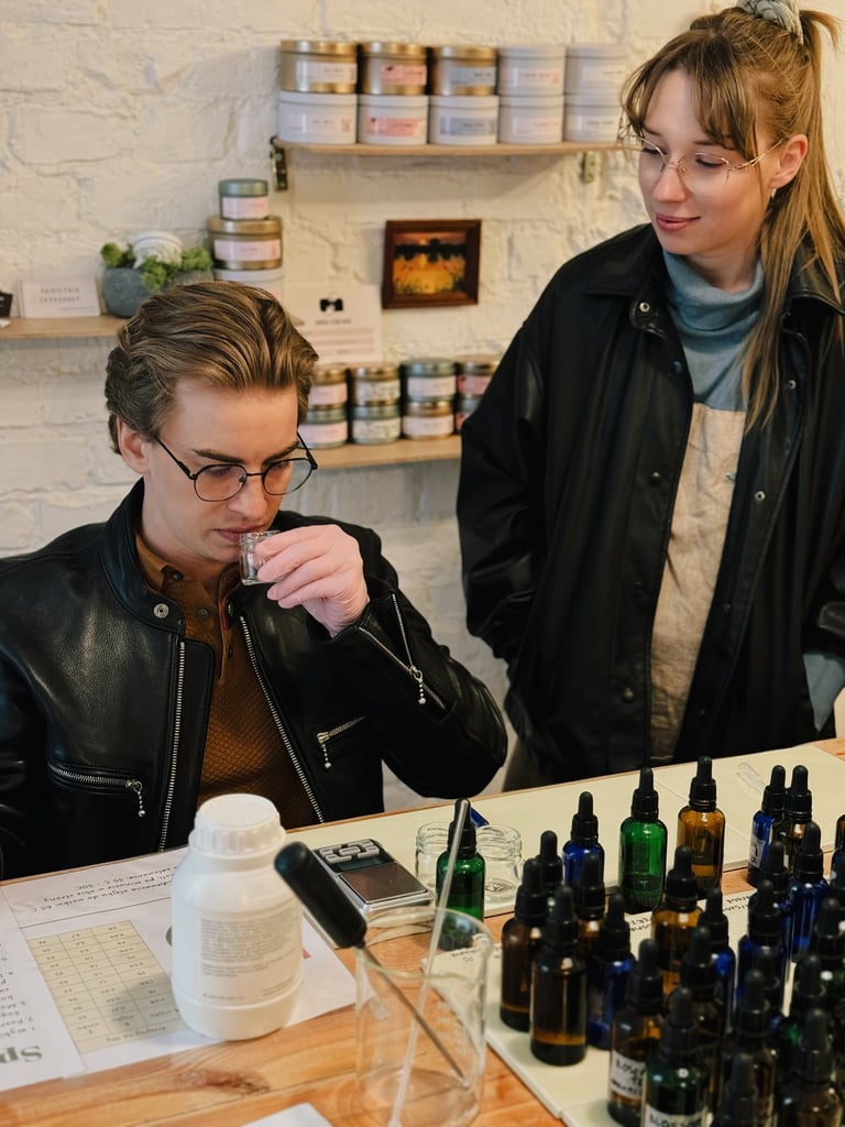 A man smells a sample at a custom perfume workshop with essential oil bottles on the table.