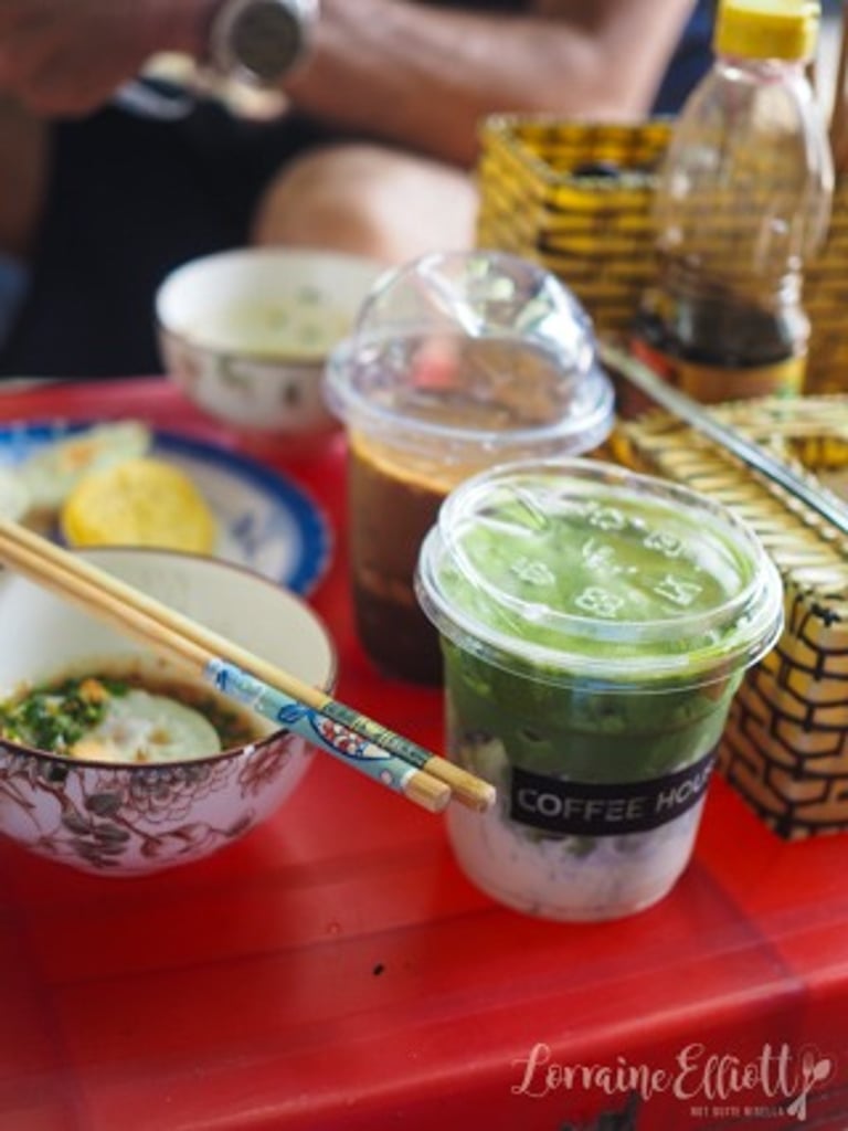 Iced matcha green tea latte and Vietnamese coffee on a red table with breakfast bowls and chopsticks.