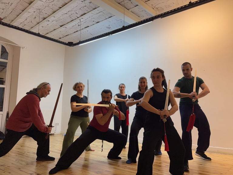 Ali Yörükoğlu's Jian class students hold sword stances in unison, focused and grounded in form, Kun, Taksim, 2025