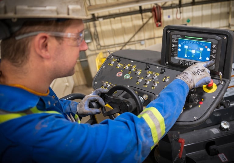 A heavy equipment technician is inspecting the hydraulic settings on a Bomag paving machine's digital dashboard 