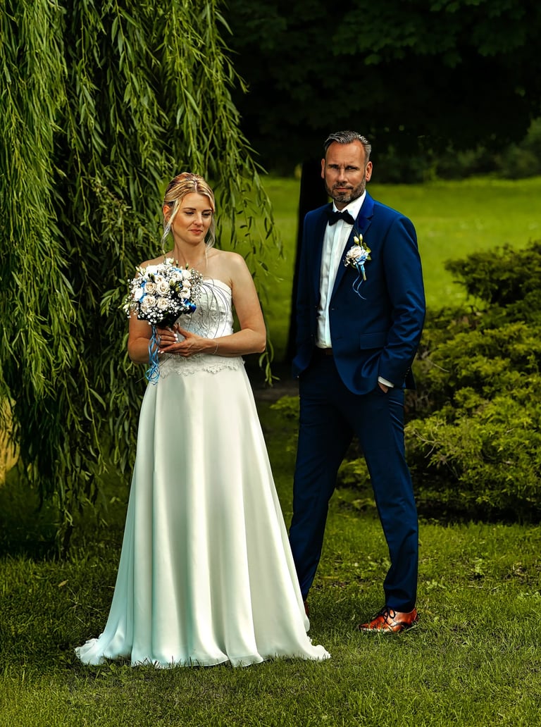 Braut mit Blumenstrauß und Bräutigam im blauen Anzug – Hochzeitsfotograf Möhnesee