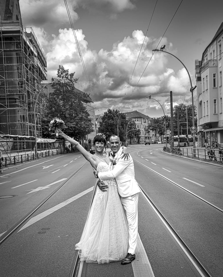 Ein schwarz-weißes Foto eines Hochzeitspaares, das sich umarmt und in die Kamera lächelt, während es in der Mitte einer leere