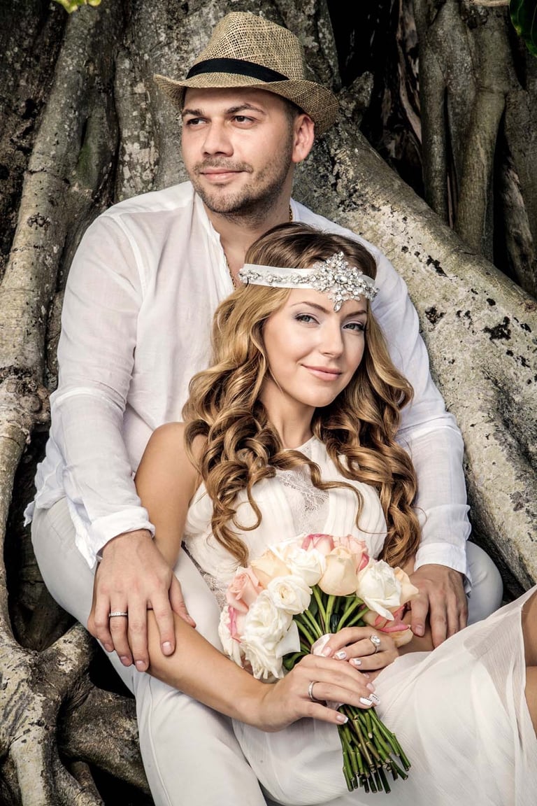 Boho wedding couple portrait seated among massive tree roots