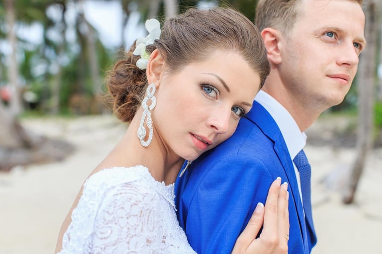 Bride rests on groom shoulder in beach wedding portrait