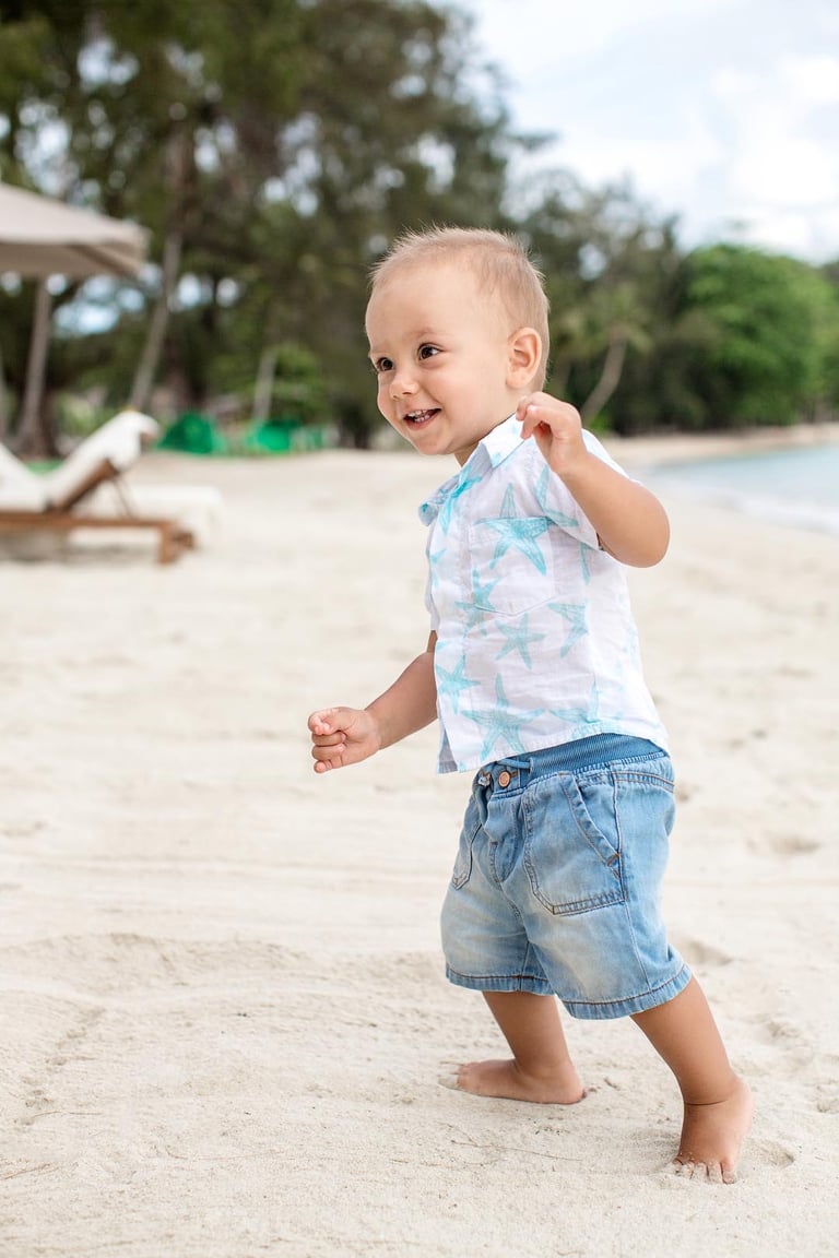 Smiling toddler walking along sandy beach in Phu Quoc