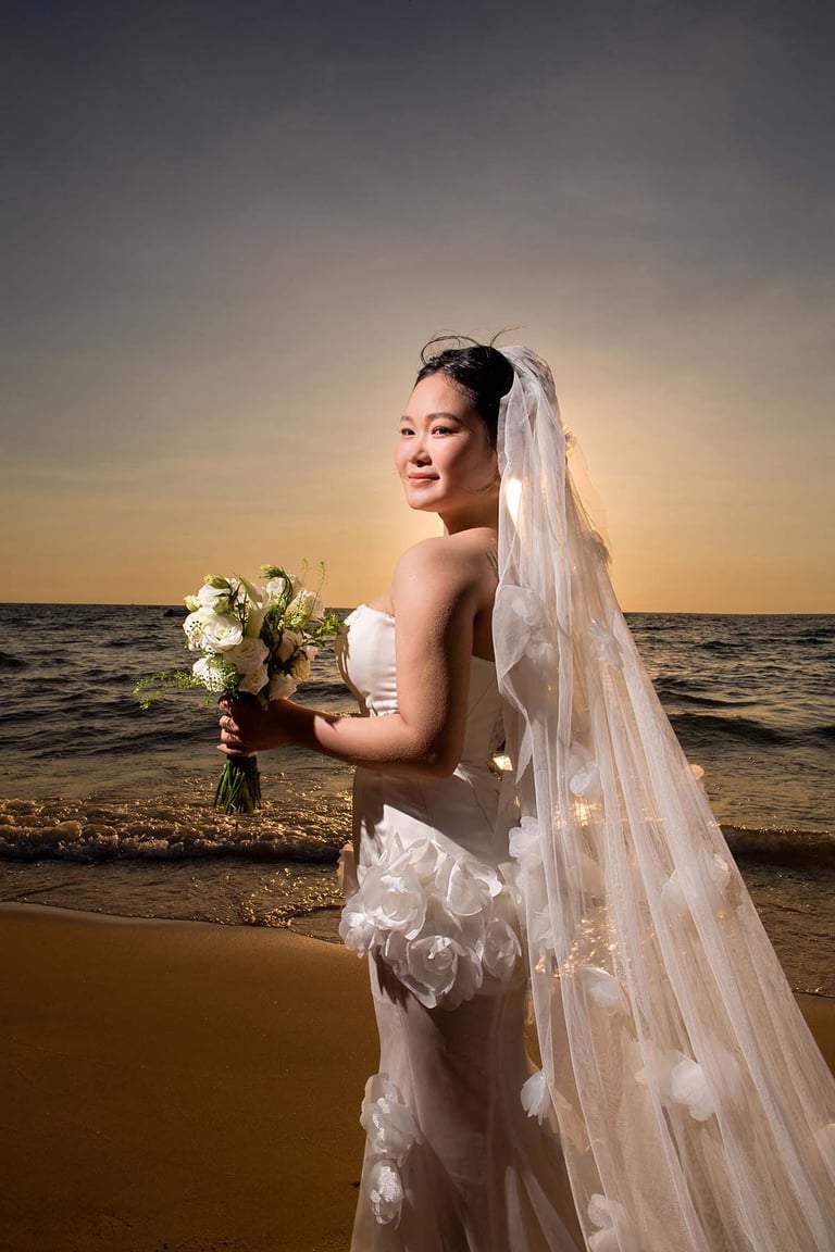 Sunset bridal portrait with veil and bouquet by sea