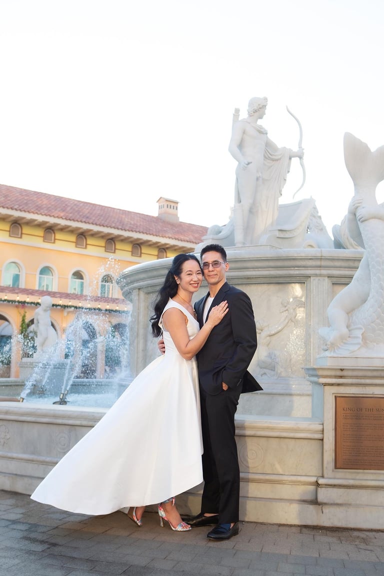 Wedding couple hugging by fountain statues in Sunset Town
