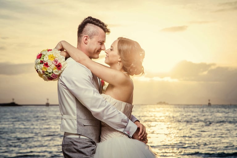 Bride and groom hugging at Sunset Town golden seafront