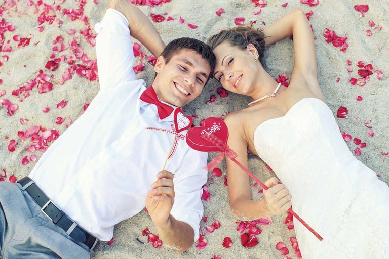 Wedding couple lying on sand with rose petals